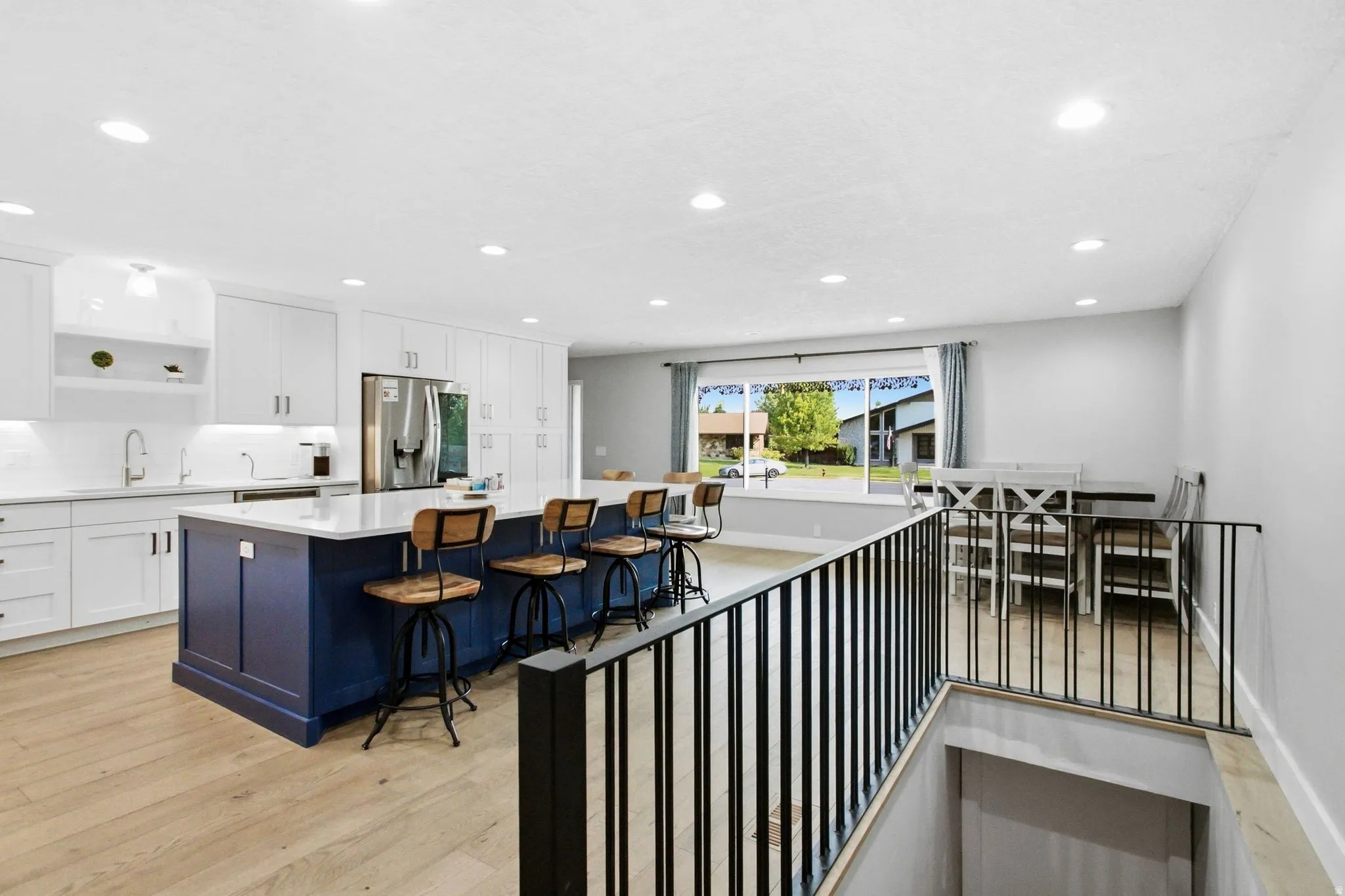 Open-concept kitchen featuring white cabinetry, a blue kitchen island with seating, a white countertop, and recessed lighting