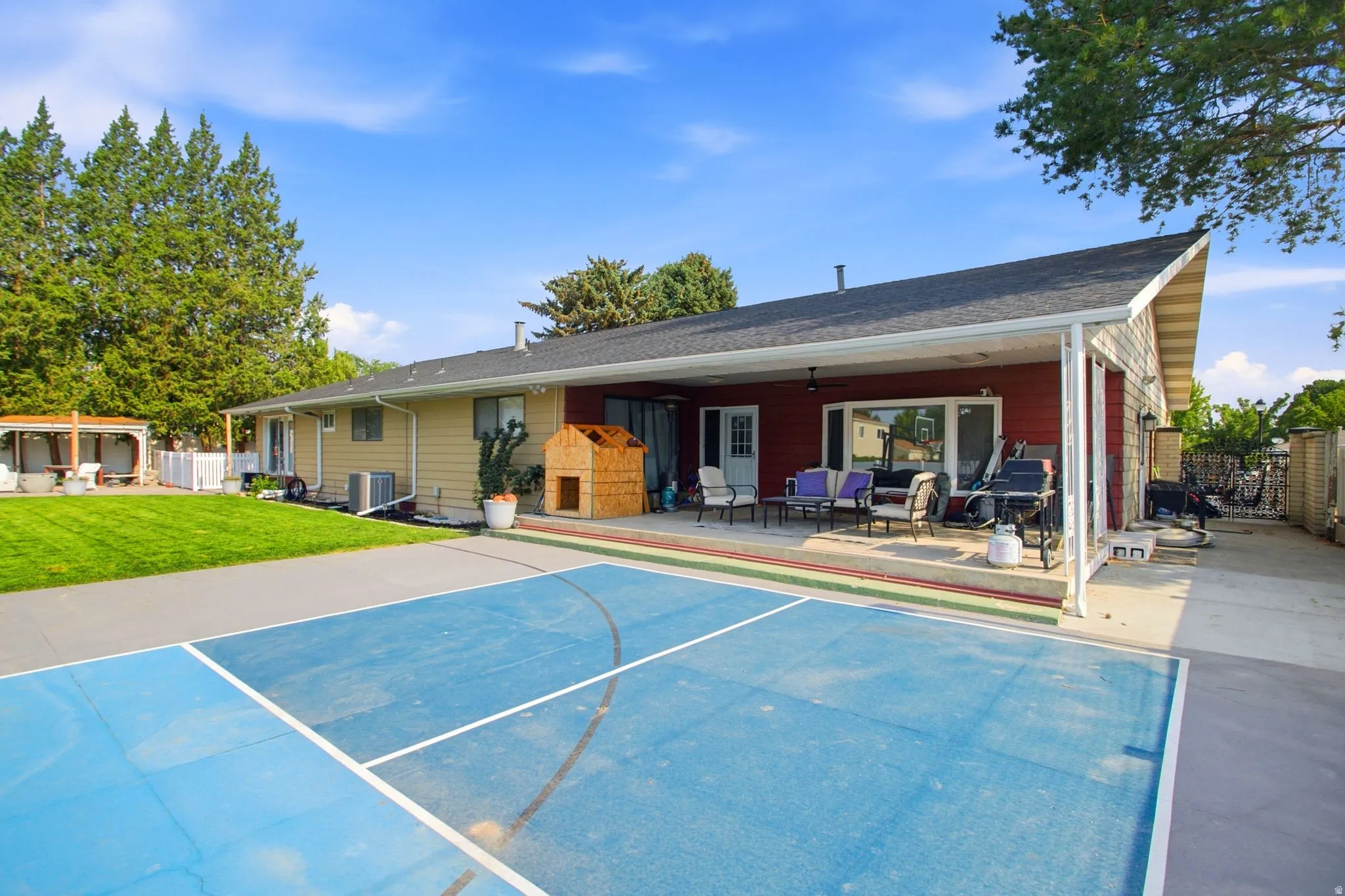 Sport court with painted lines and a covered patio featuring a red siding accent