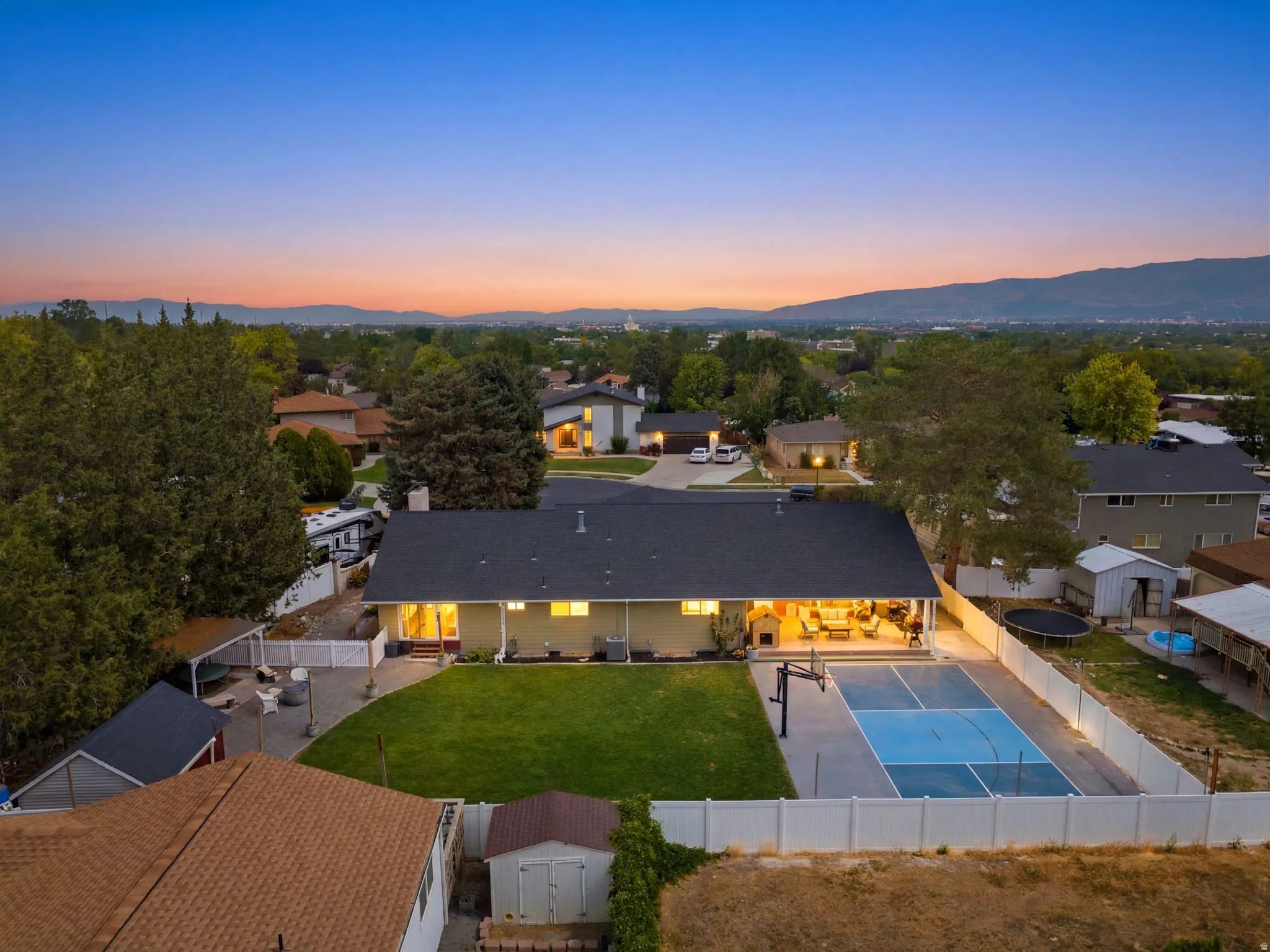 Expansive backyard featuring a manicured lawn, full-size basketball court, and private covered patio