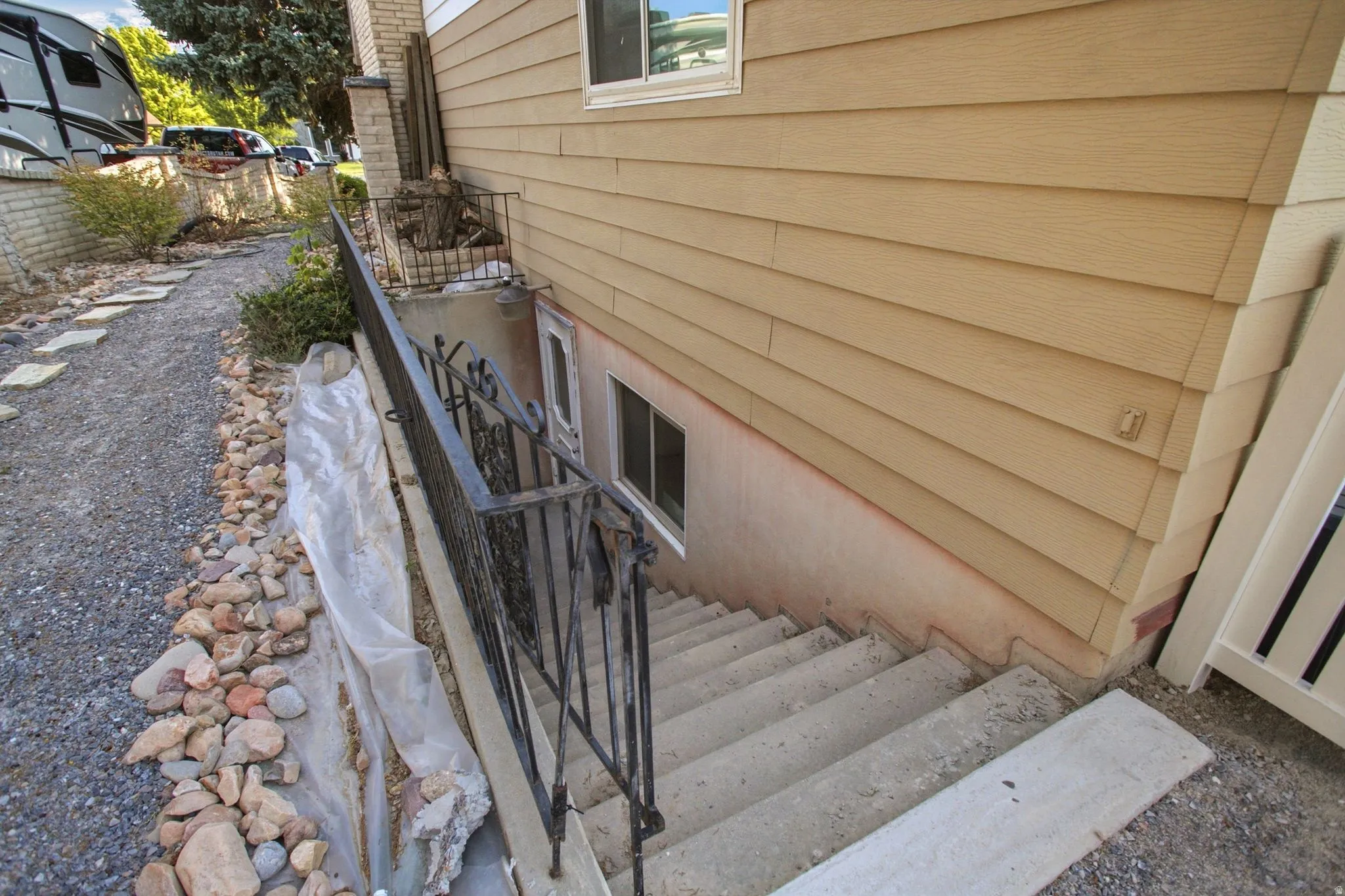 Concrete staircase with wrought iron railing leading to a lower-level window