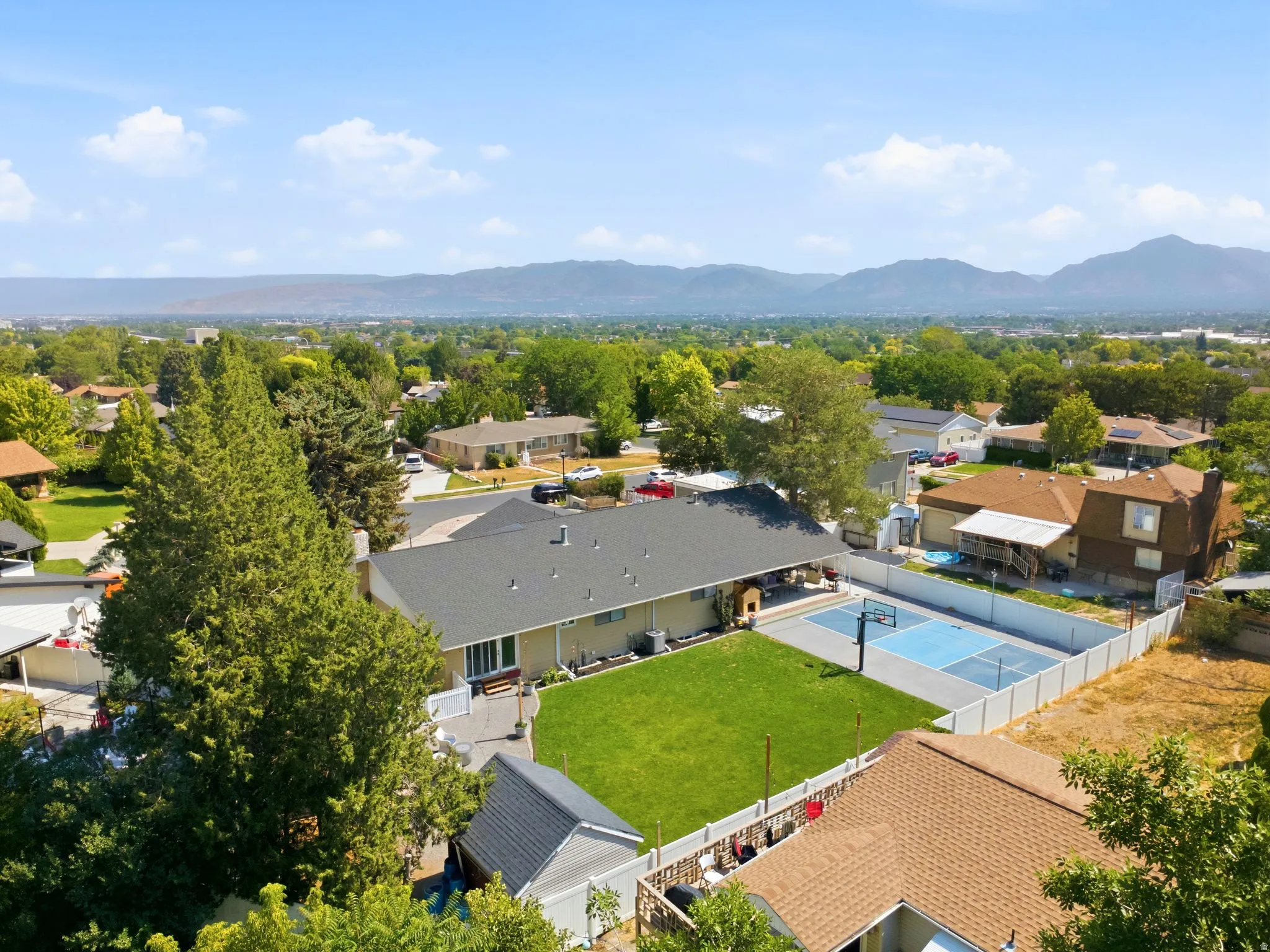 Expansive backyard featuring a lush lawn, dedicated sports court, and mature trees