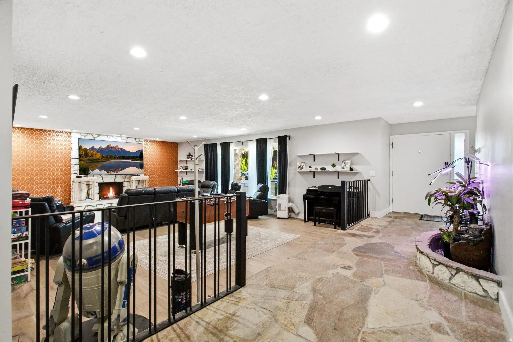Spacious living area featuring a prominent stone fireplace, recessed lighting, and a unique accent wall