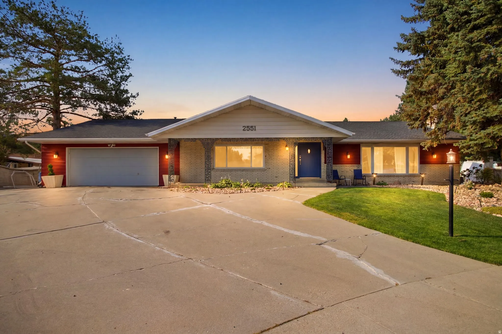 Ranch-style residence featuring a prominent two-car garage, concrete driveway, and established front landscaping