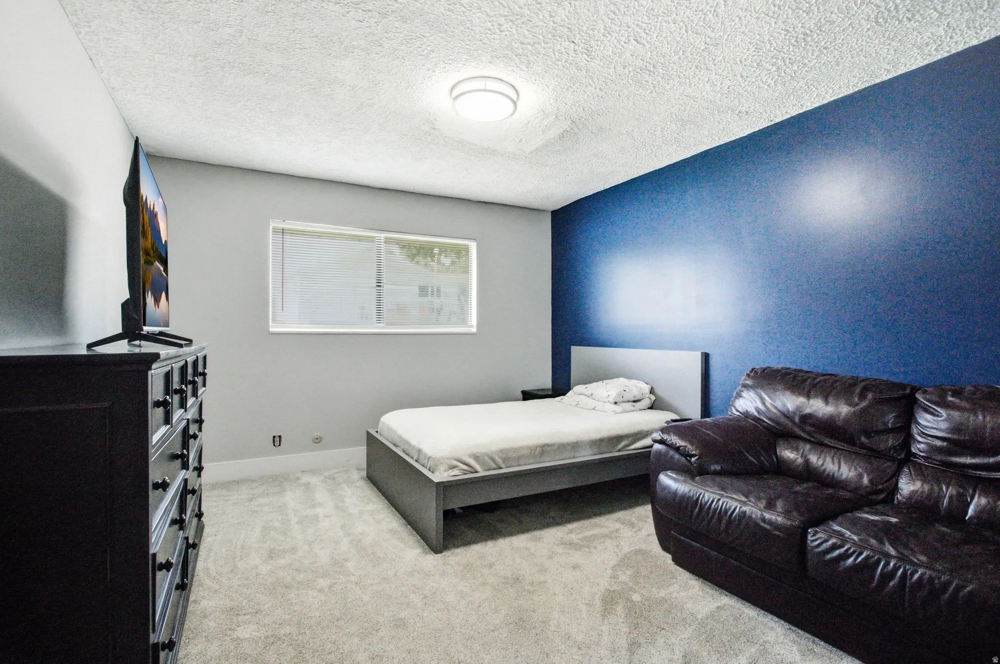 Room featuring light gray walls, a contrasting blue accent wall, and light-colored carpeting