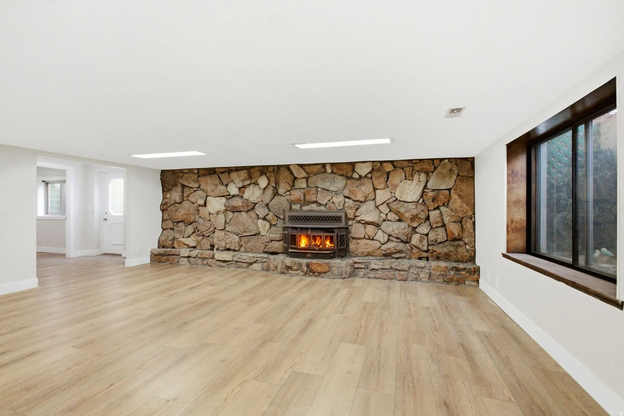 Spacious room featuring a prominent stone wall with an integrated wood-burning stove