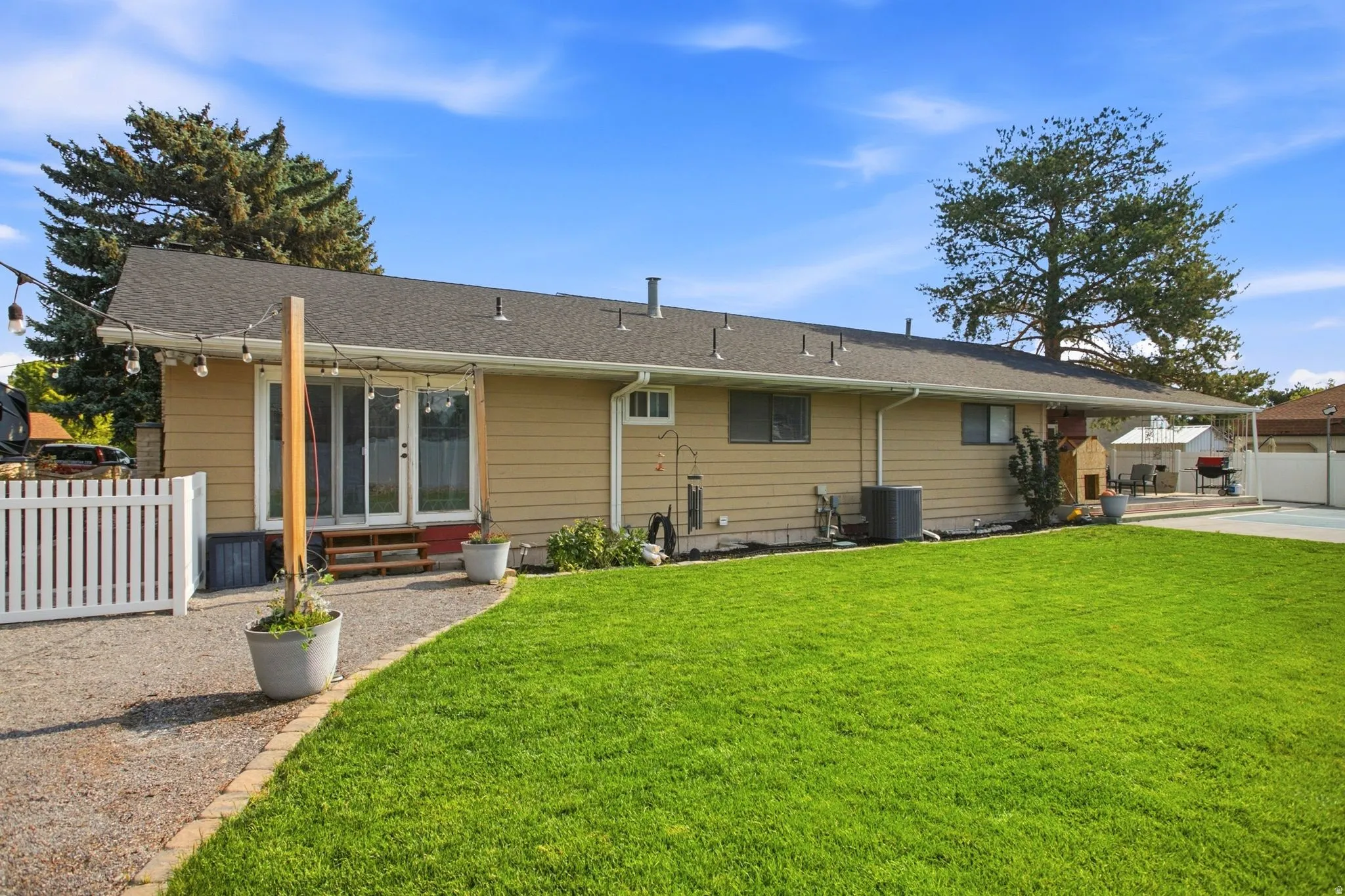 Expansive backyard featuring a lush lawn, gravel patio, and double glass doors