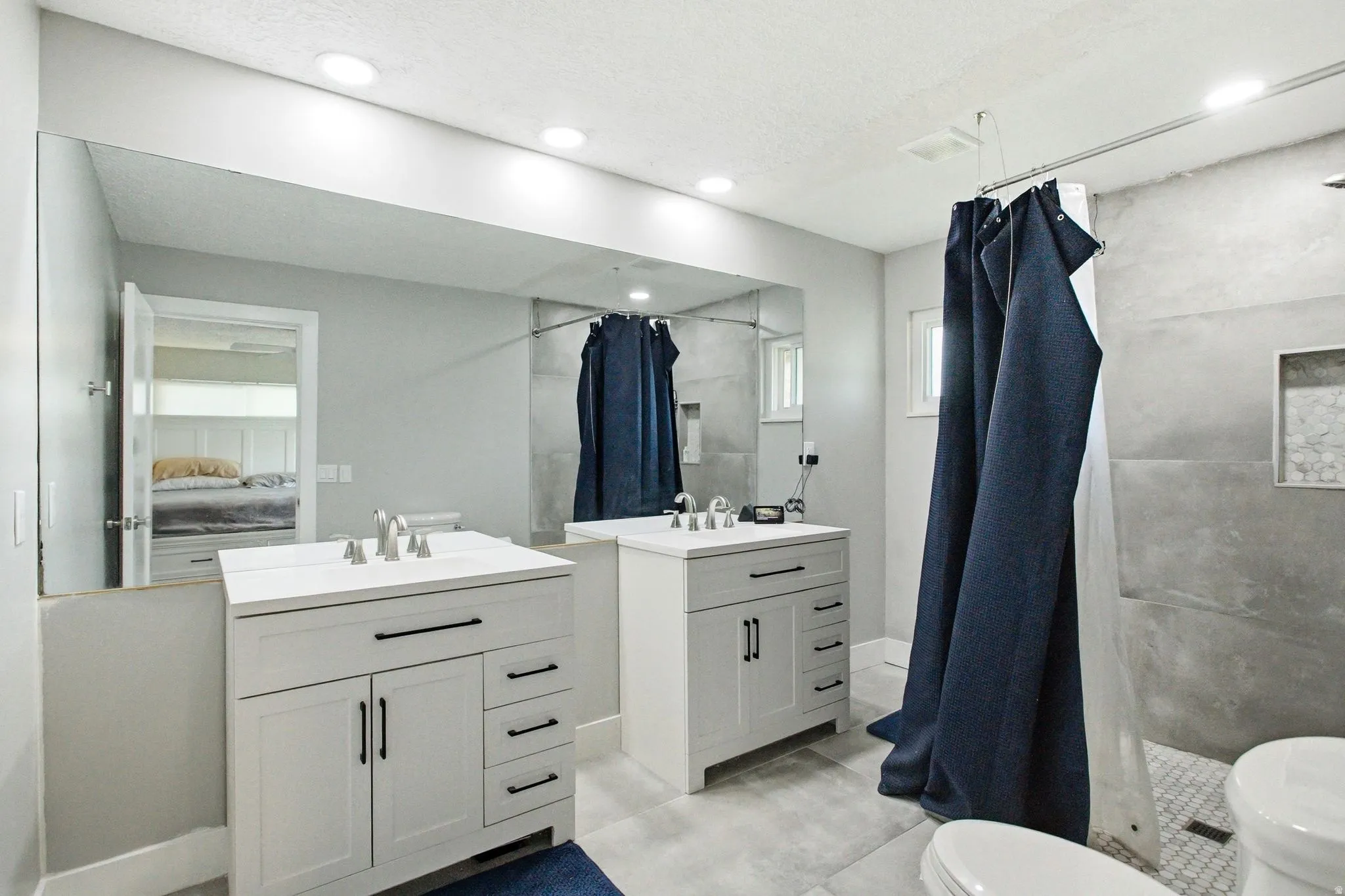 Dual vanity bathroom featuring recessed lighting, a large wall-mounted mirror, and tile flooring