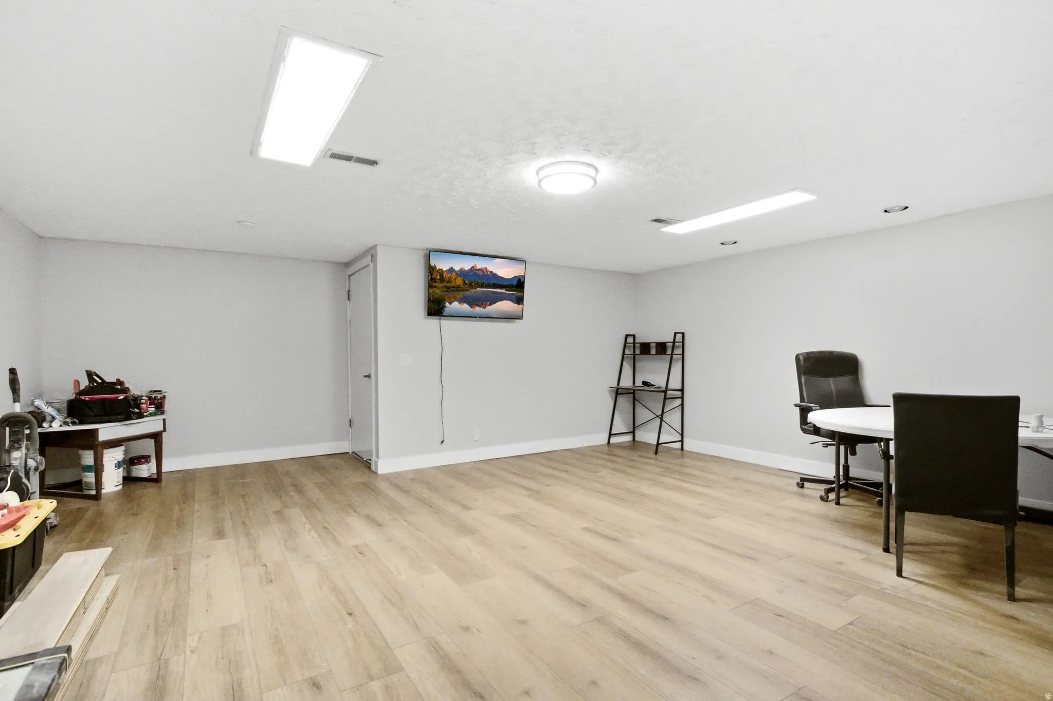 Spacious room featuring wood-finish flooring, light grey walls, and white baseboards