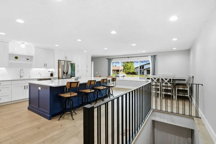 Open-concept kitchen featuring white cabinetry, a blue kitchen island with seating, a white countertop, and recessed lighting