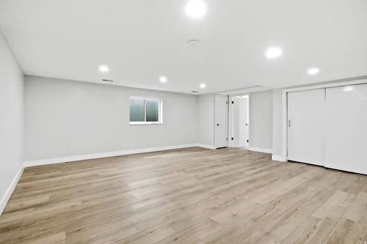 Spacious room featuring light wood-finish flooring, recessed lighting, and a neutral wall palette