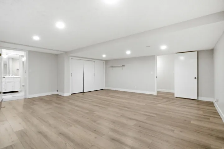Spacious room featuring wood-finish flooring, recessed lighting, and bright white walls