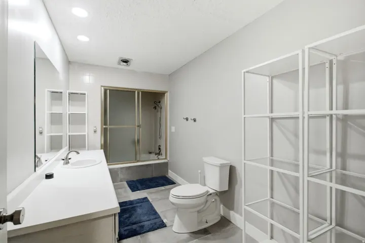 Bathroom featuring a single vanity with an integrated sink, large wall-mounted mirror, and recessed lighting