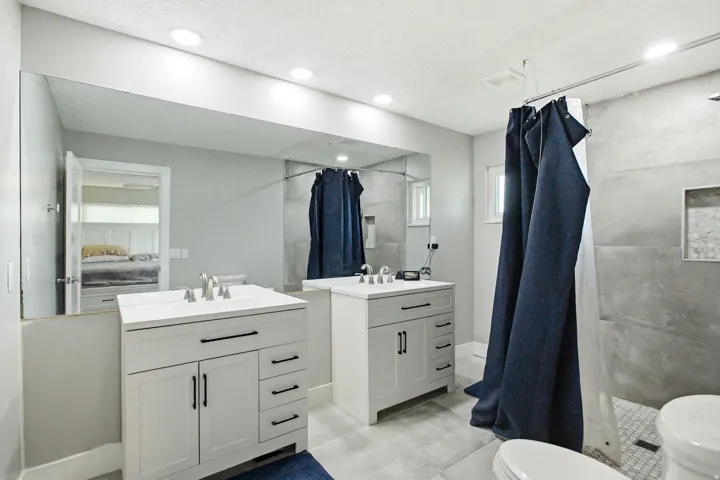 Dual vanity bathroom featuring recessed lighting, a large wall-mounted mirror, and tile flooring