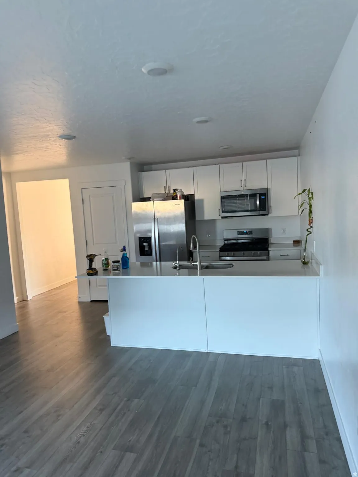 Modern kitchen featuring white cabinetry, stainless steel appliances, and a central island with integrated sink