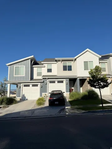 Modern townhome exterior with mixed material siding, featuring two attached garages and individual driveways