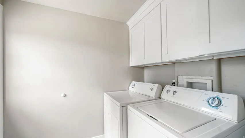 Laundry area featuring white cabinetry and light-toned walls
