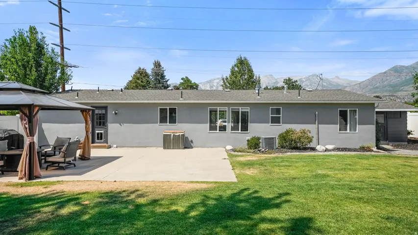 Expansive backyard featuring a large concrete patio, manicured lawn, and a mountain backdrop