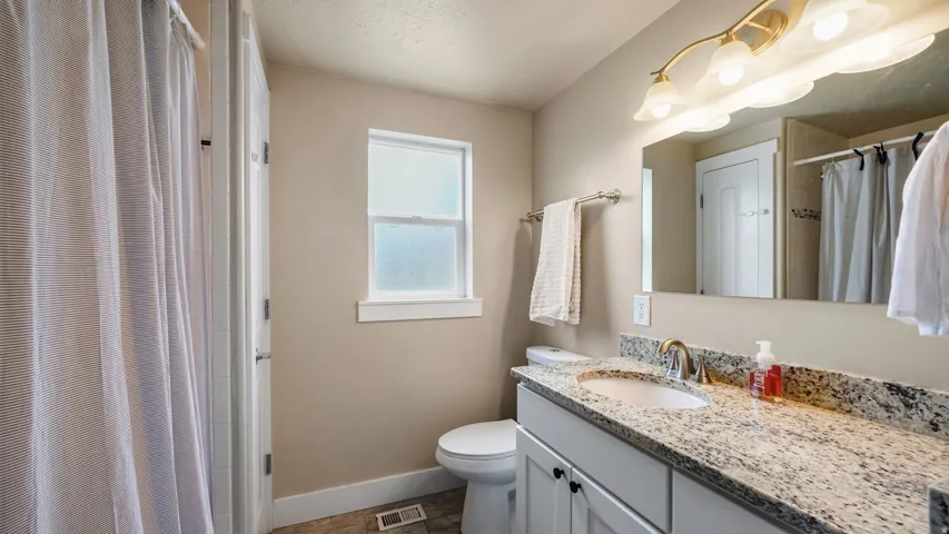 Bathroom featuring a white vanity with a speckled countertop, undermount sink, and brushed nickel faucet