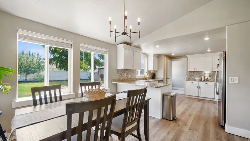 Open-concept dining area featuring wood-finish flooring and a contemporary chandelier