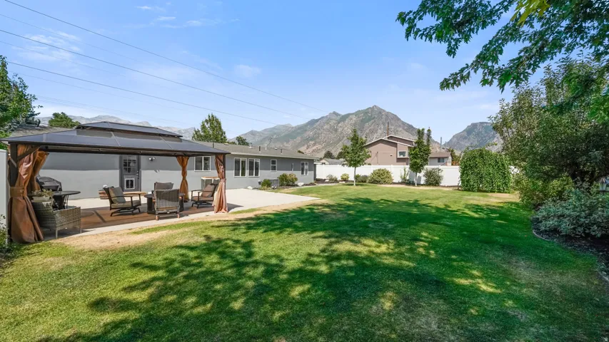 Expansive backyard featuring a manicured lawn, a large patio, and a covered outdoor living area