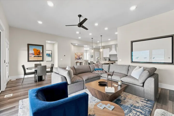 Open-concept living space featuring wood-finish flooring, recessed lighting, and a dark-toned ceiling fan