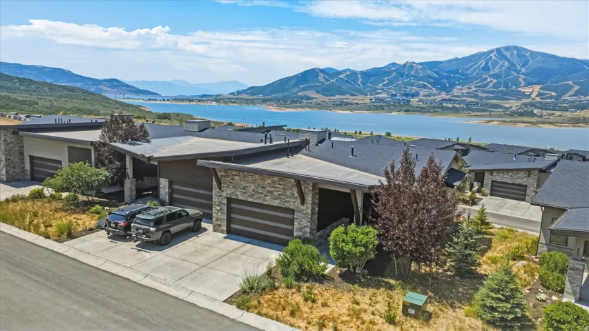Contemporary residence featuring stacked stone and stucco exterior finishes, a dark shingle roof, and an attached two-car garage