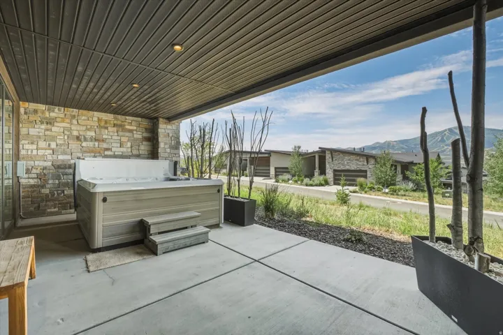 Covered patio featuring a built-in spa, stone accent wall, recessed lighting, and a concrete slab