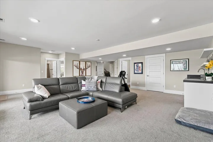 Carpeted recreation room featuring recessed lighting, a built-in wet bar with a stainless steel sink, flat panel shaker style doors, and painted trim