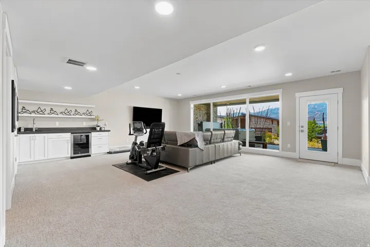 Spacious carpeted room featuring a built-in wet bar with white cabinetry and dark countertops