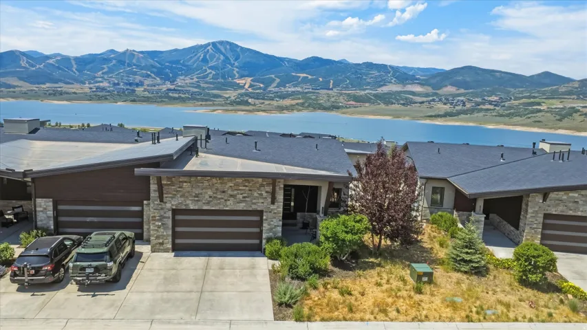 Contemporary residence featuring stone and wood-look siding, multiple garages, and a sloped roofline