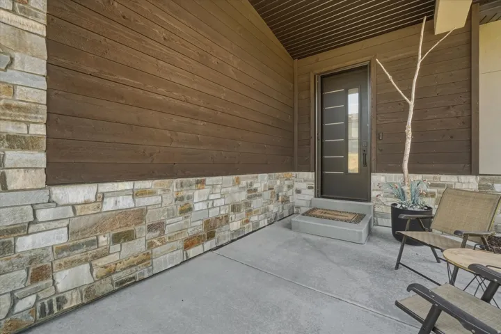 Covered entryway featuring wood-finish siding and stone veneer