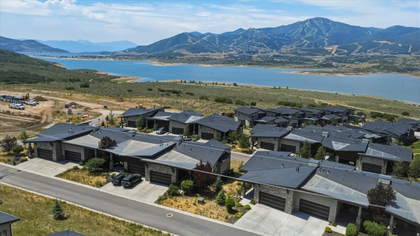 Modern townhome community featuring stone and stucco exteriors with dark roofs, concrete driveways, and integrated garages