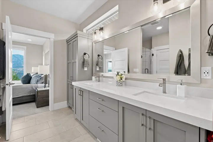 Bathroom featuring a dual vanity with light gray cabinetry, white countertops, and brushed nickel fixtures