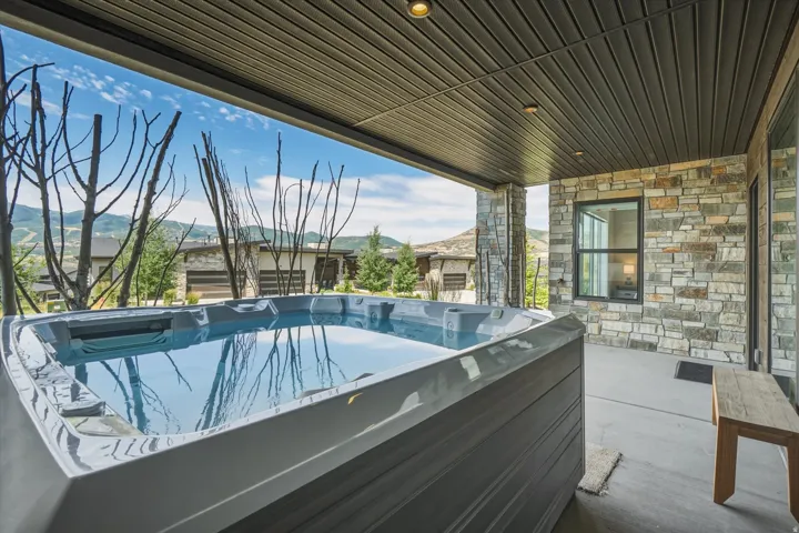Outdoor patio featuring a built-in hot tub, concrete flooring, and a stone accent wall