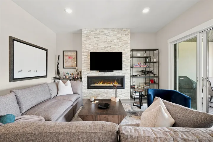 Living area featuring a floor-to-ceiling stacked stone fireplace surround with a linear electric fireplace