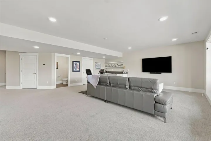 Spacious recreation room featuring light-colored carpeting, recessed lighting, and pale neutral wall tones