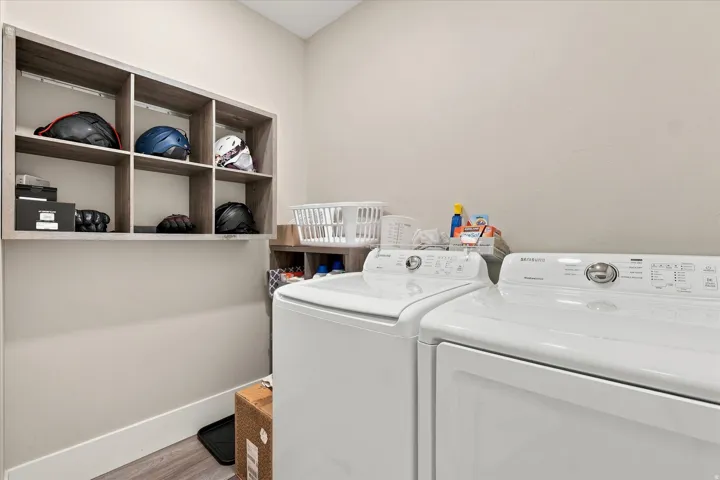 Laundry area featuring wood-finish flooring, light-colored wall paint, and a built-in wall storage unit with open shelving