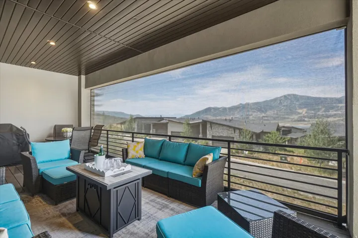 Expansive covered patio featuring a slatted ceiling with recessed lighting, an opaque roller shade, and a horizontal bar railing