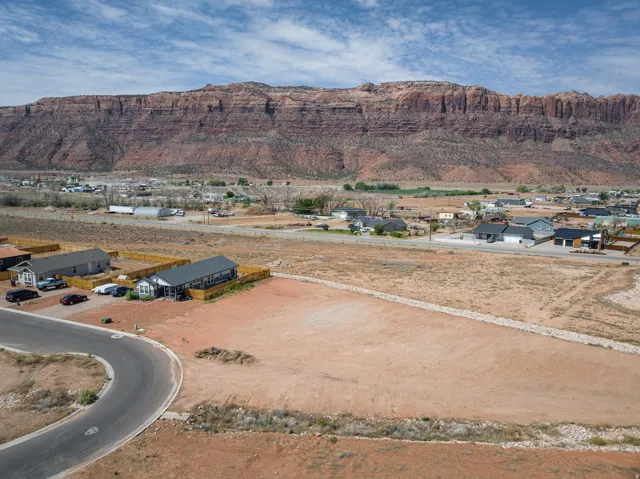 Expansive land parcel featuring a paved cul-de-sac and desert landscaping, set against a prominent mountain backdrop