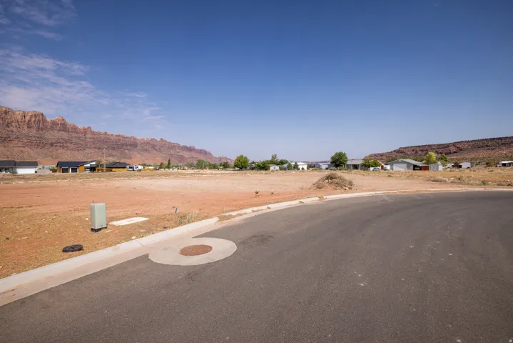 Expansive land parcel featuring a paved road frontage and surrounding desert landscape