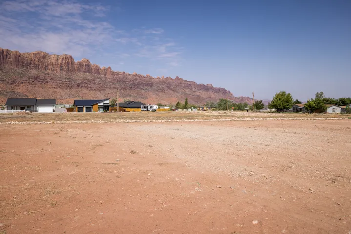 Expansive undeveloped lot featuring a red earth surface and a distant mountain range backdrop
