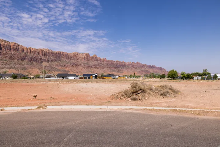 Expansive unimproved lot featuring red-toned earth and a clear mountain backdrop