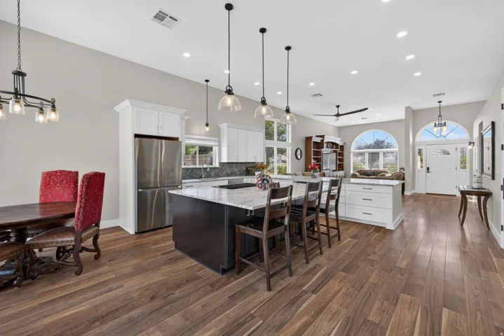 Open-concept living space with wood-finish flooring, vaulted ceilings, and recessed lighting