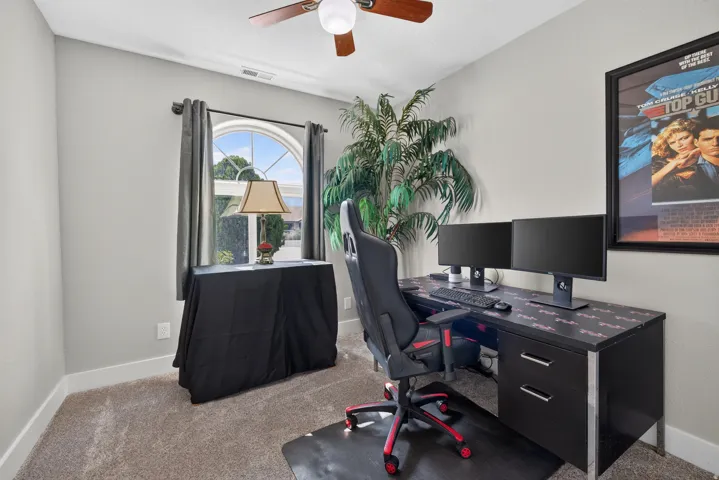 Room featuring light gray walls, plush carpet flooring, a ceiling fan with integrated lighting, and a prominent arched window
