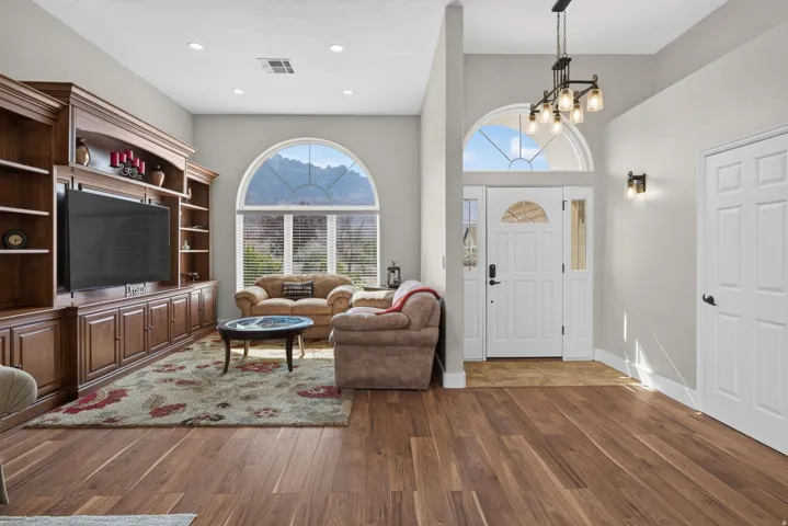 Spacious living area featuring rich wood-finish flooring and a built-in entertainment center with extensive cabinetry