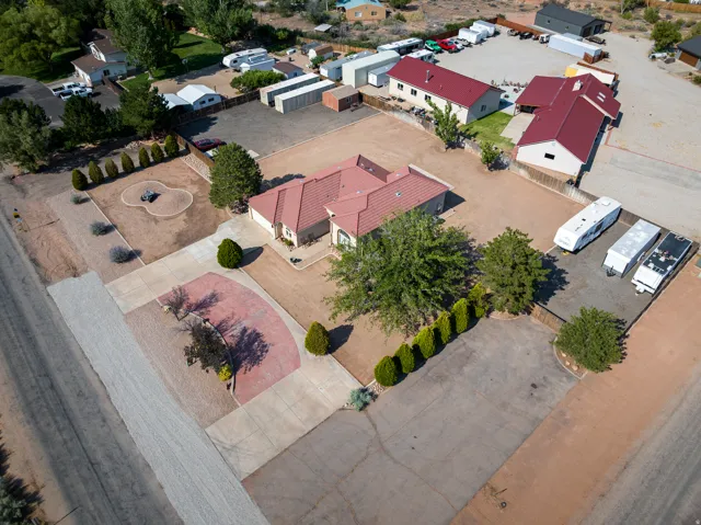 Expansive property featuring a central residence with a red-tiled roof, multiple outbuildings, and extensive paved and gravel parking areas