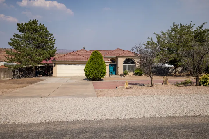 Southwestern-style residence featuring a terracotta-tiled roof and an attached garage with a light-colored door