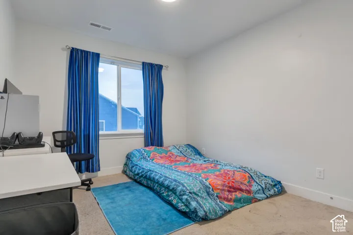 Room with light beige carpet flooring, white walls, and a single window with blue curtains