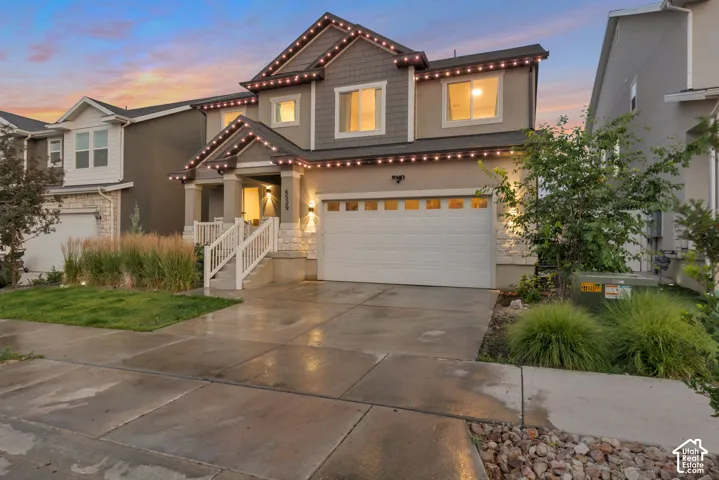 Two-story residence featuring a covered entry porch, white railings, and a two-car garage