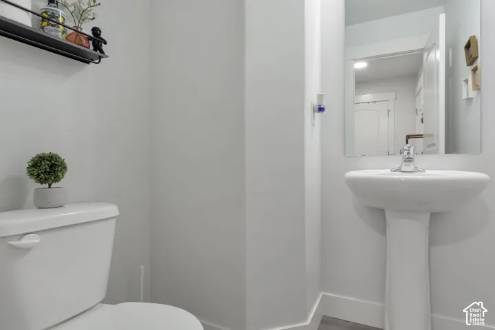 White pedestal sink with chrome faucet, complemented by a wall-mounted mirror